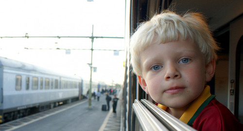Barn som tittar ut från ett tågfönster över en tågperrong.