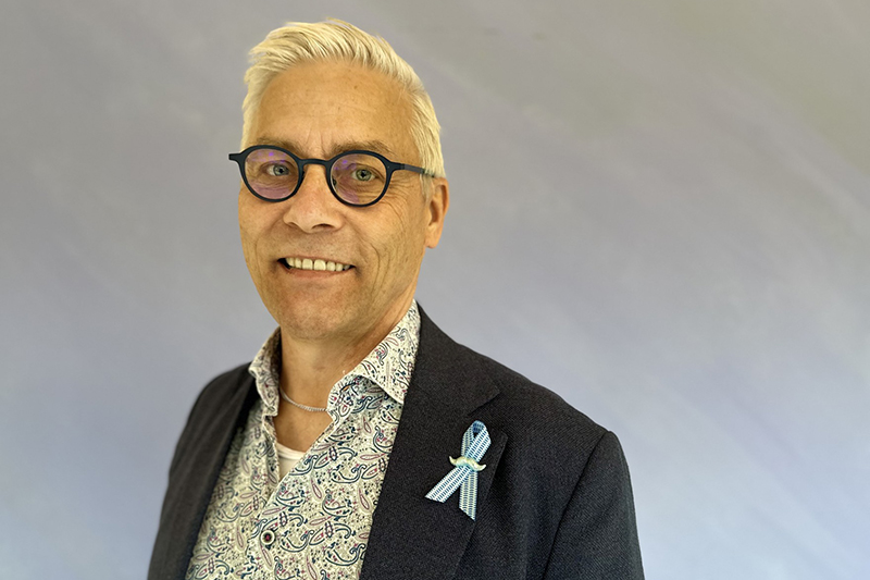 Leende person i kort ljust hår glasögon och kavaj