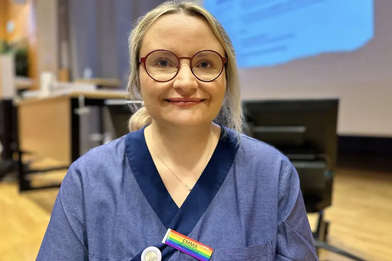 Person i vårdkläder ler mot kameran.