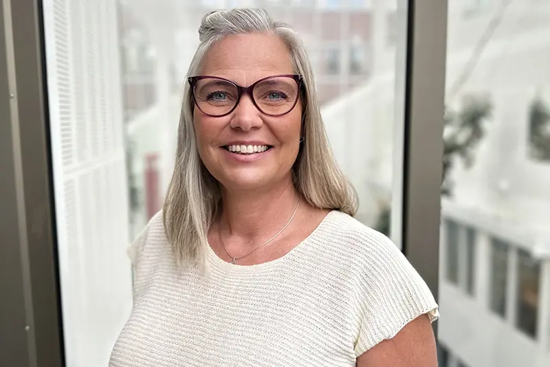 Person i vit tröja ler mot kameran.