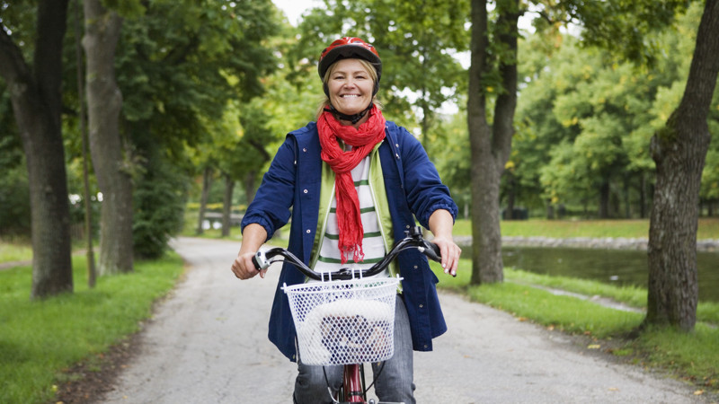 Leende kvinna som cyklar mot kameran.