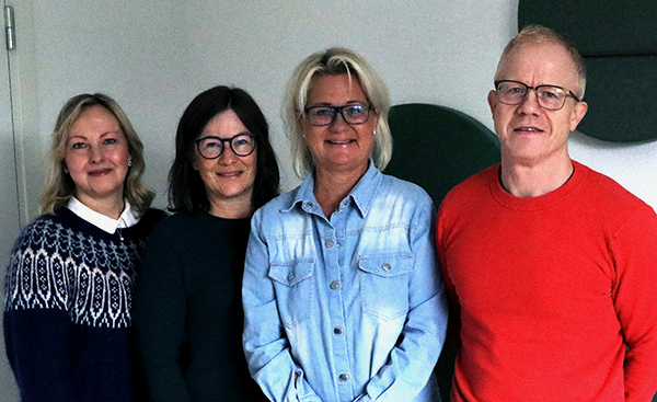 Tre kvinnor och en man står bredvid varandra och tittar in i kameran. 