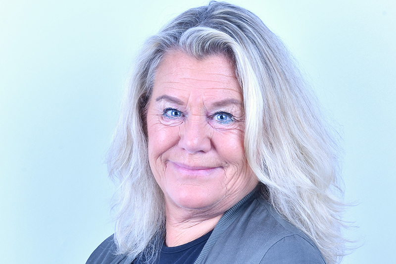 Närbild på leende person med blont hår och blå ögon