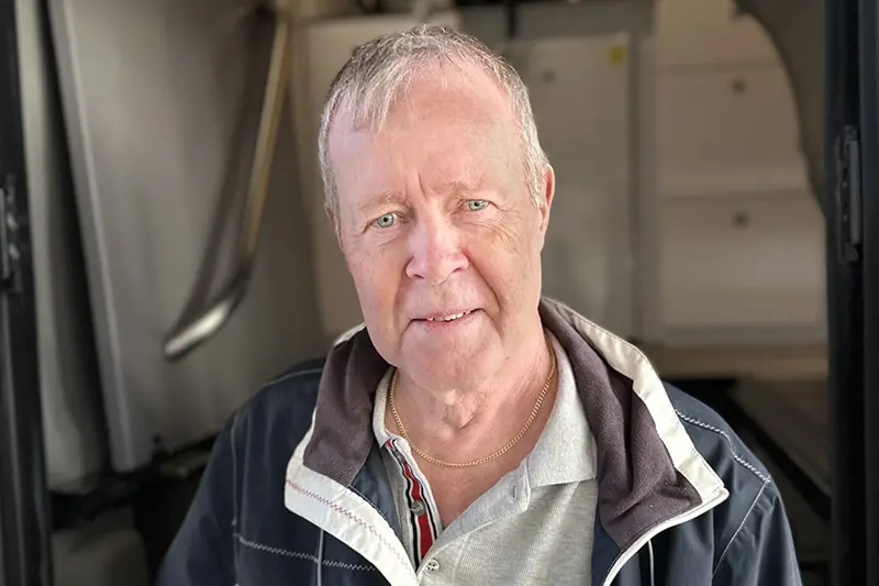 En person i kort frisyr tittar in i kameran.