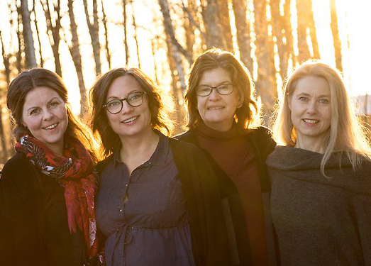 fyra kvinnor står utomhus i motljus