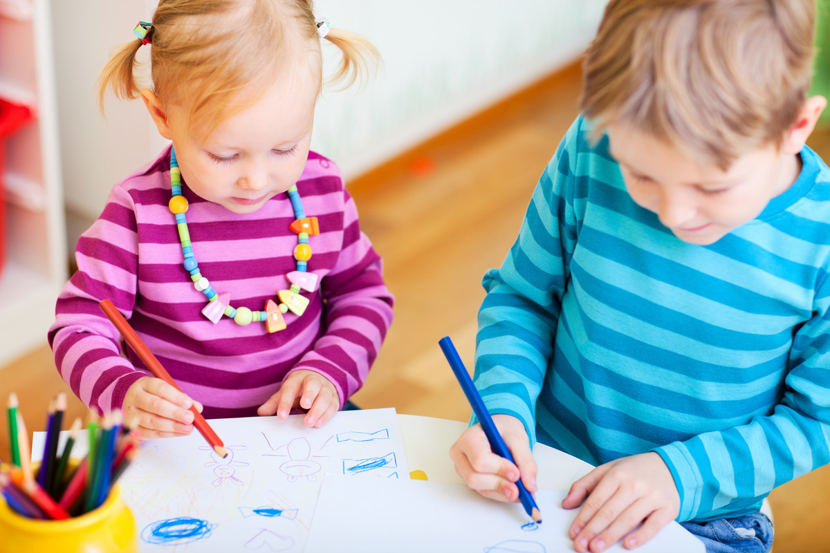 Två barn med randiga färgglada tröjor som ritar