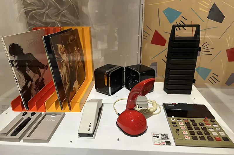 En röd cobratelefon och en räknemaskin i en glasmonter