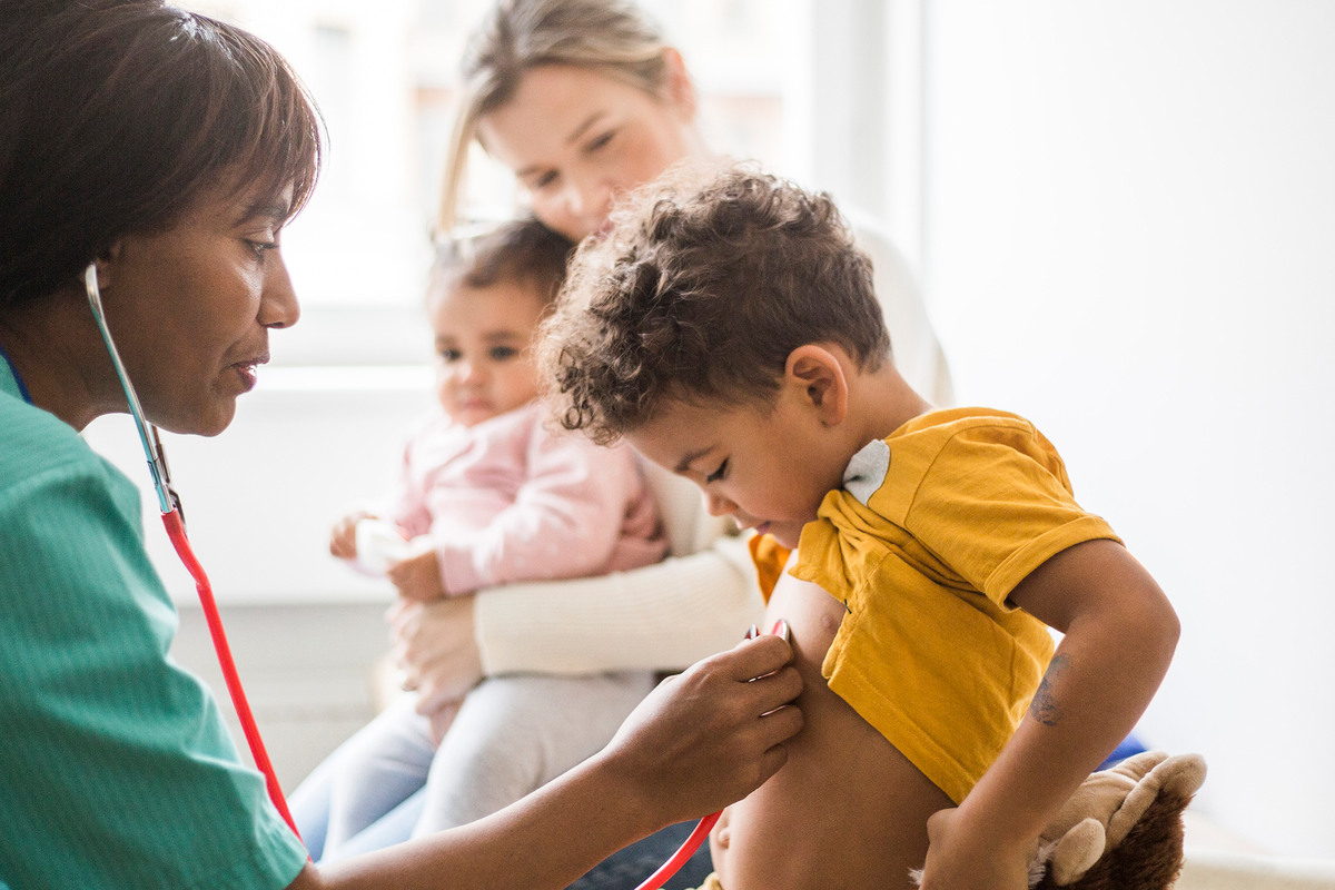 En läkare lyssnar med stetoskop på ett barns bröstkorg.