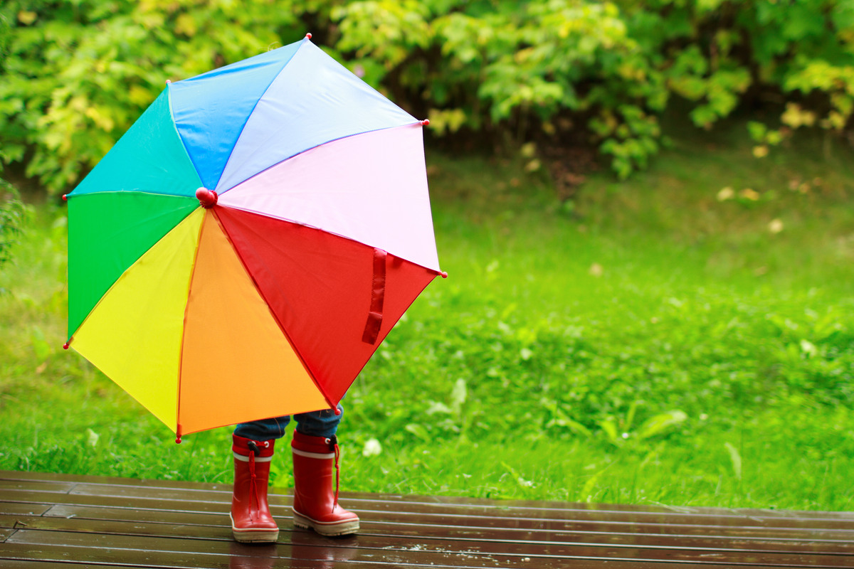 Barn som gömmer sig bakom ett flerfärgat paraply.