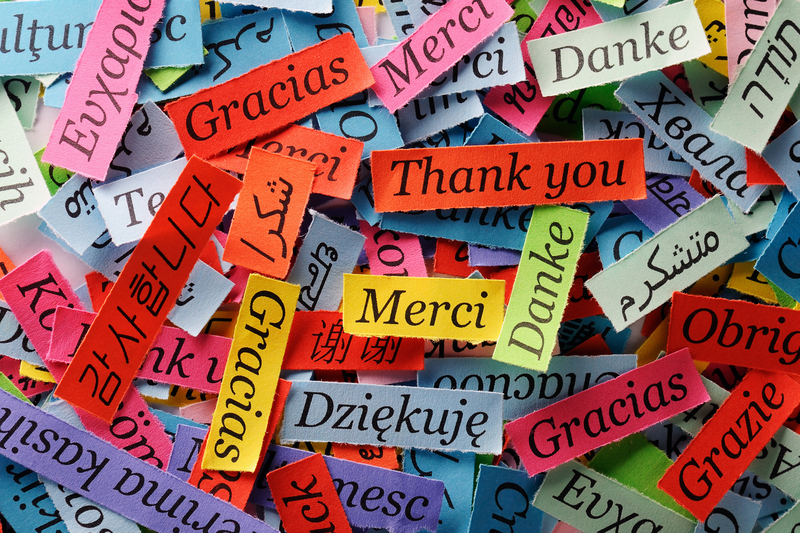 Ordet tack på olika språk skrivet på färgglada lappar.
