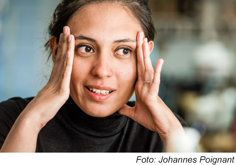 Kvinna som håller sina händer på sidan om ansiktet och blickar samtidigt låt sidan Foto: Johannes Poignant