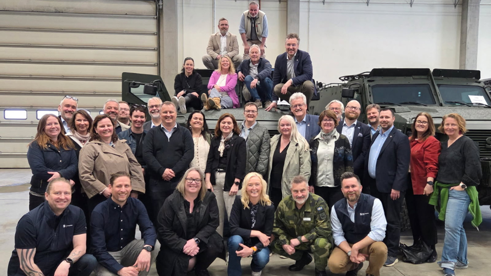 Gruppbild på ett trettiotal personer i en företagslokal. 