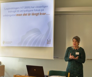 En kvinna står i en föreläsningssal framför en presentationsskärm