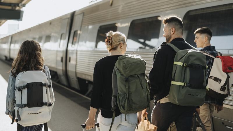 Familj med packning går och pratar på en tågperrong.