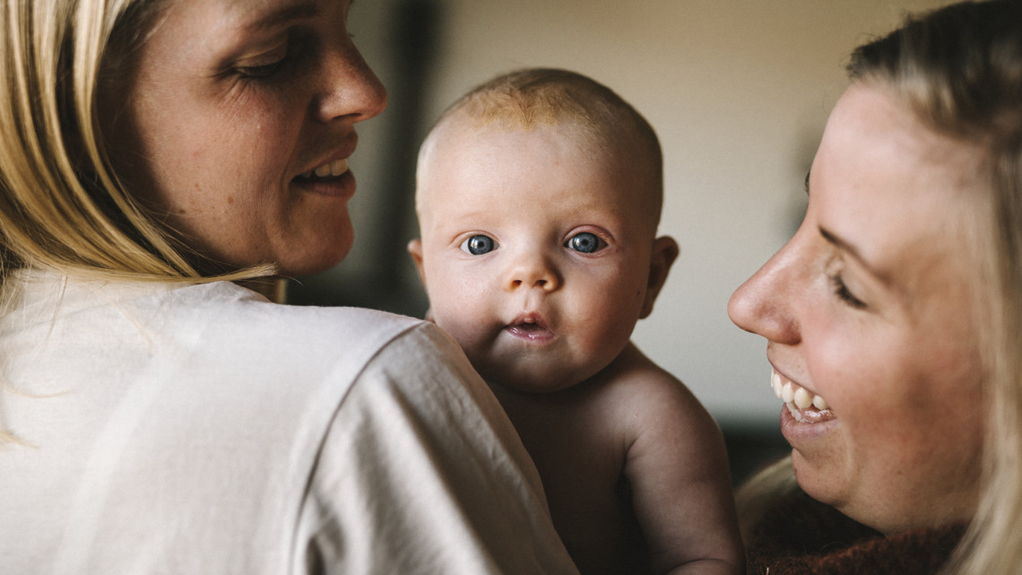 Två skolungdomar pratar och ler sittandes på en buss.