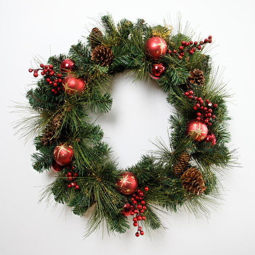 Juldekoration i form av en krans av gran, röda bär och röda julkulor.