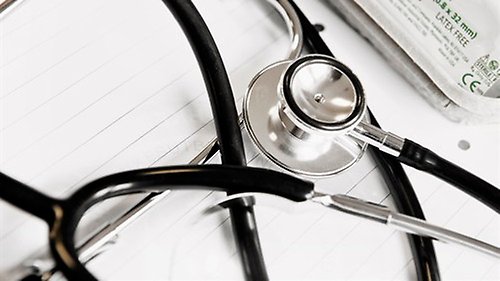 Stetoskop som ligger ihopvirat över ett kontorspapper.