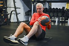 Man som gör övningar i krokliggande för coremuskulaturen med boll. 