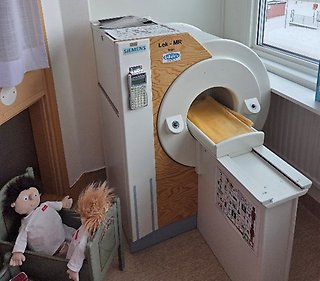 En säng med dockor och en leksaks magnetrötgenkamera