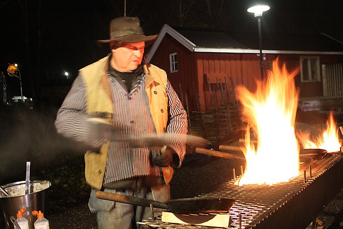 En person står vid öppen eld och lagar kolbullar