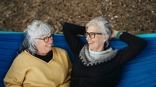 Två personer ligger tillsammans i en hängmatta och pratar med varandra och skrattar.