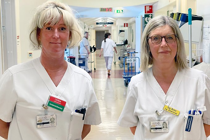 Två personer i vårdkläder som står i en korridor på en vårdavdelning.
