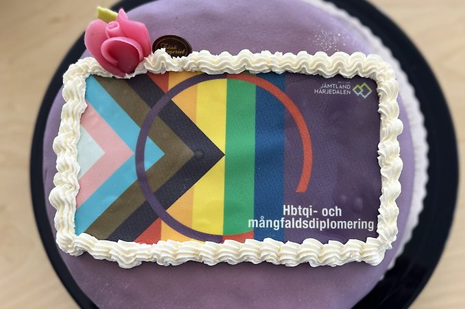 En lila marsipantårta dekorerad med pride- och transfärger och med texten "hbtqi- och mångfaldsdiplomering"