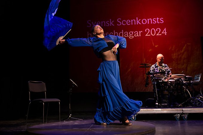 En kvinna dansar på en scen.